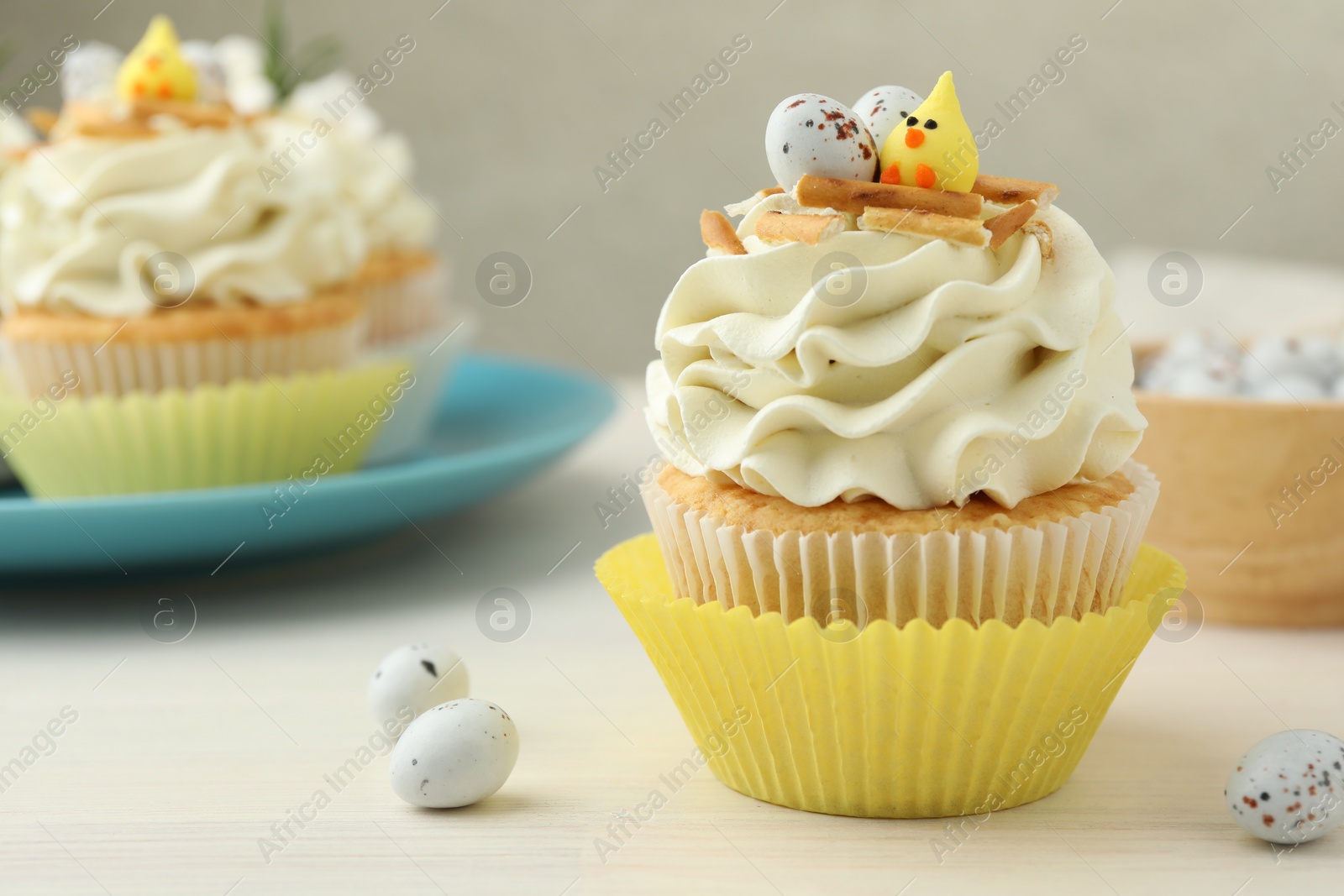 Photo of Tasty Easter cupcakes with vanilla cream on light wooden table