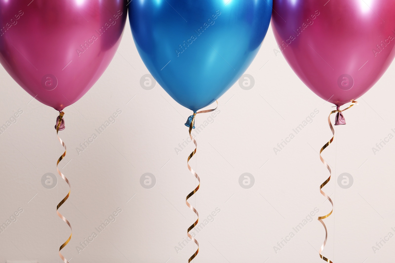 Photo of Color balloons with ribbons on white background, closeup. Space for text