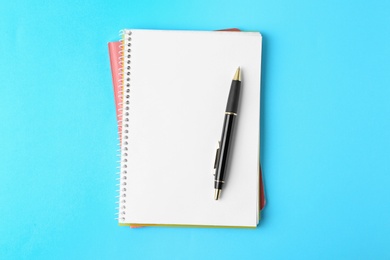 Photo of Notebooks and pen on light blue background, top view