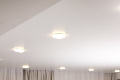 Photo of White stretch ceiling with spot lights in room