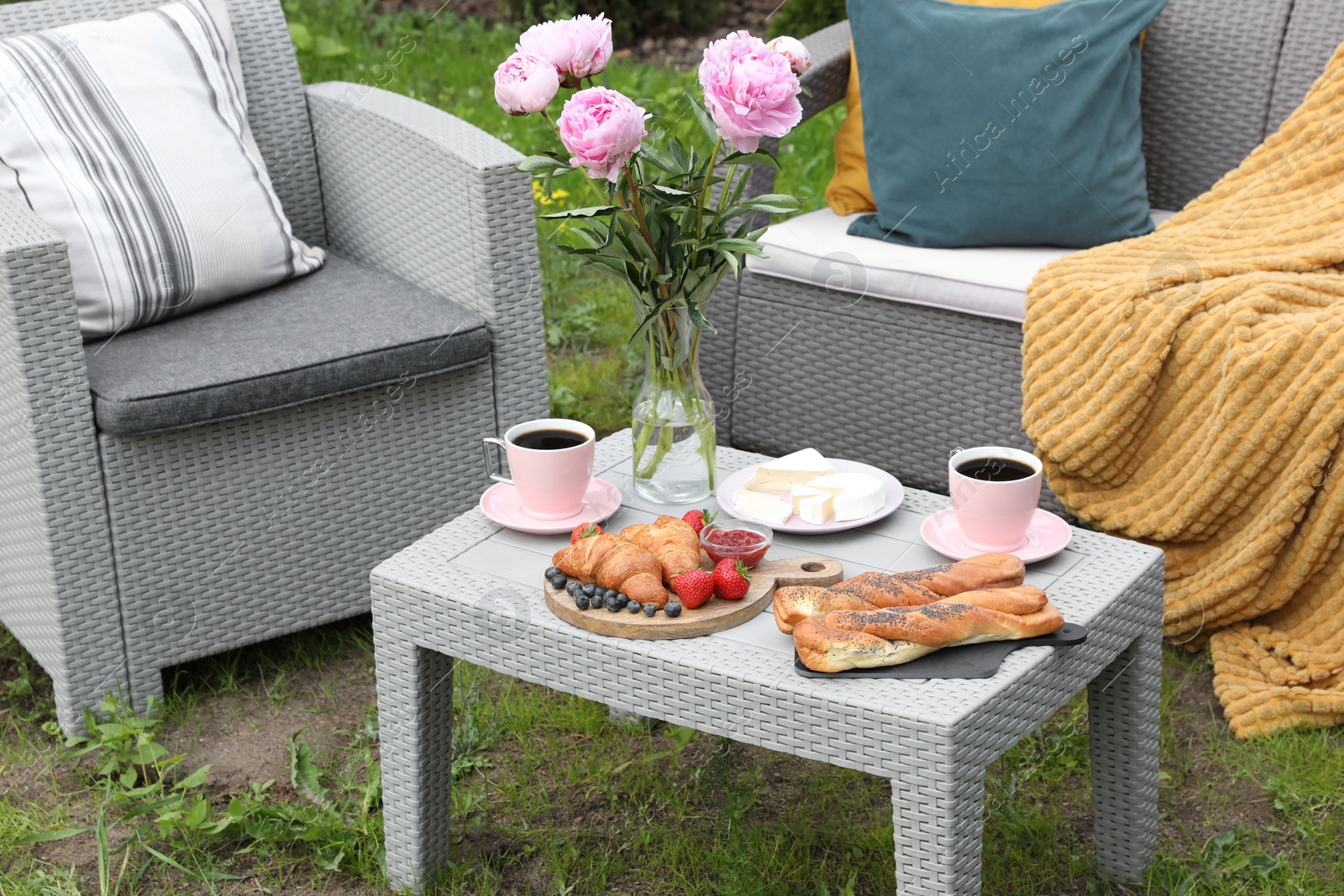 Morning drink, pastry, berries, cheese and vase with flowers on rattan table. Summer breakfast outdoors Photo of Morning drink, pastry, berries, cheese and vase with flowers on rattan table. Summer breakfast outdoors