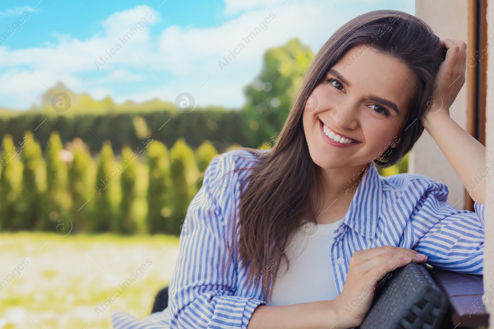 Photo of Portrait of beautiful young woman sitting on chair at backyard, space for text