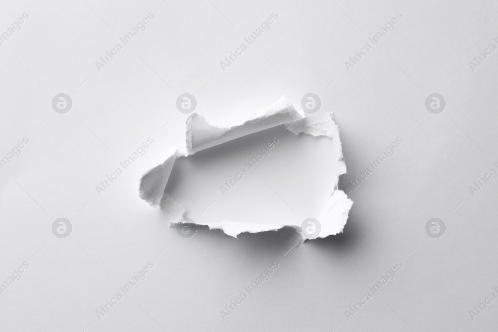 Photo of Hole in white paper on light background