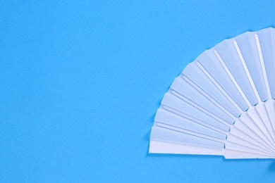 Photo of White hand fan on light blue background, top view. Space for text