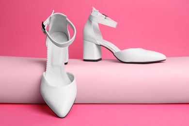 Photo of Stylish white female shoes on pink background