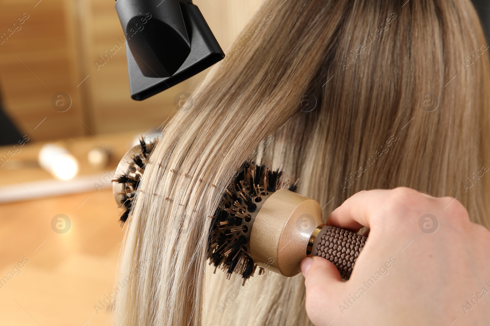 Photo of Hairdresser blow drying client's hair in salon, closeup