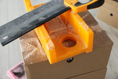 Photo of Saw and miter box for decorative brick installation indoors, closeup