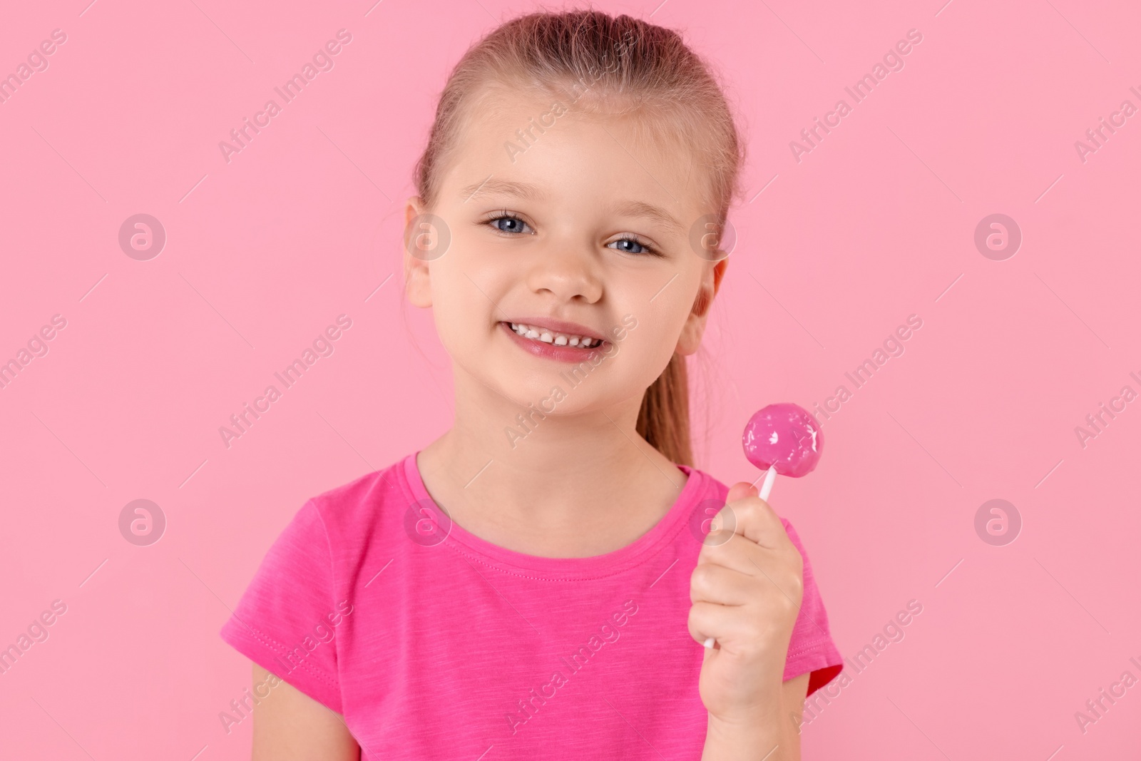 Photo of Happy little girl with lollipop on pink background