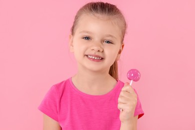 Happy little girl with lollipop on pink background