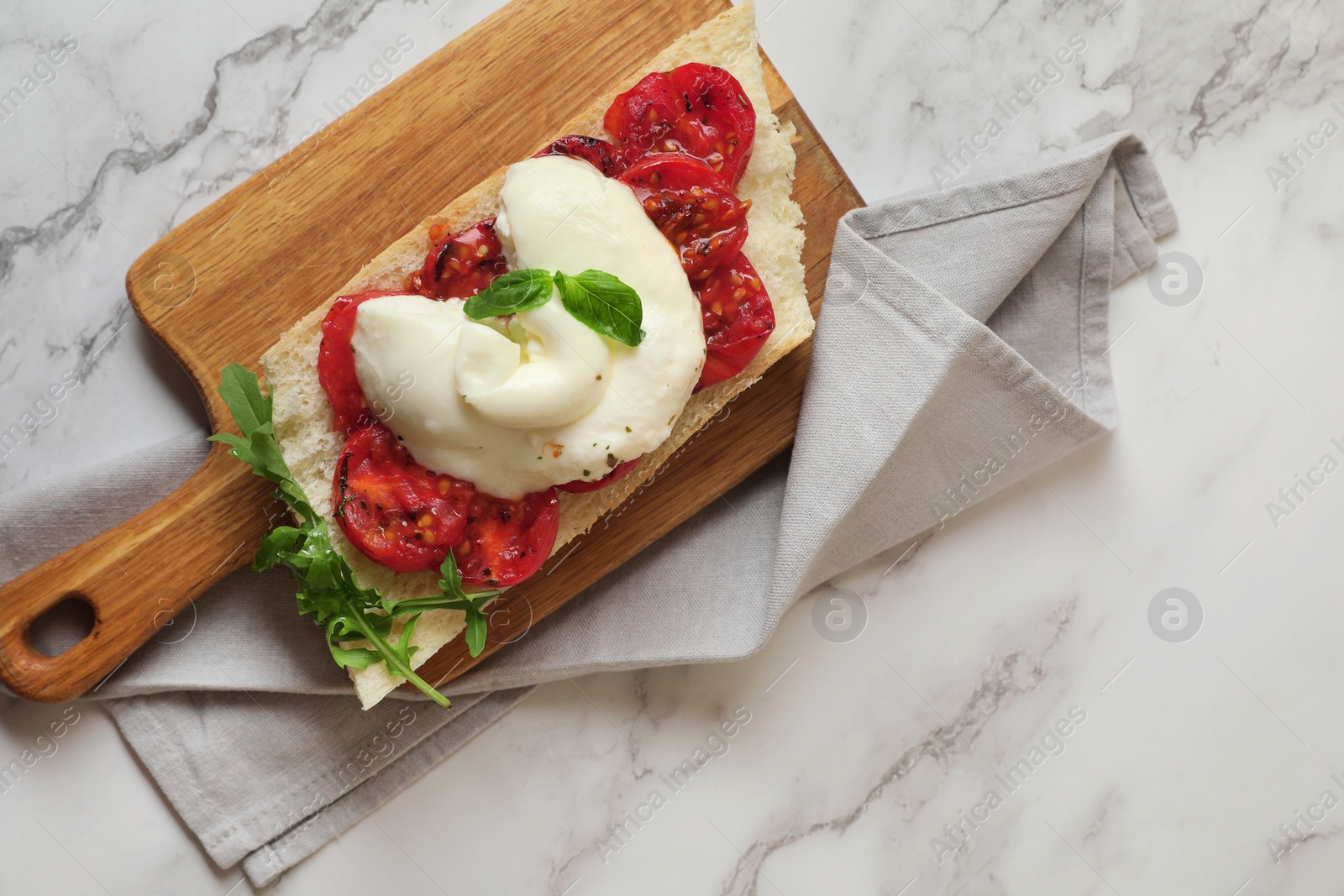 Photo of Toast with delicious burrata cheese, tomatoes and arugula on white marble table, top view. Space for text