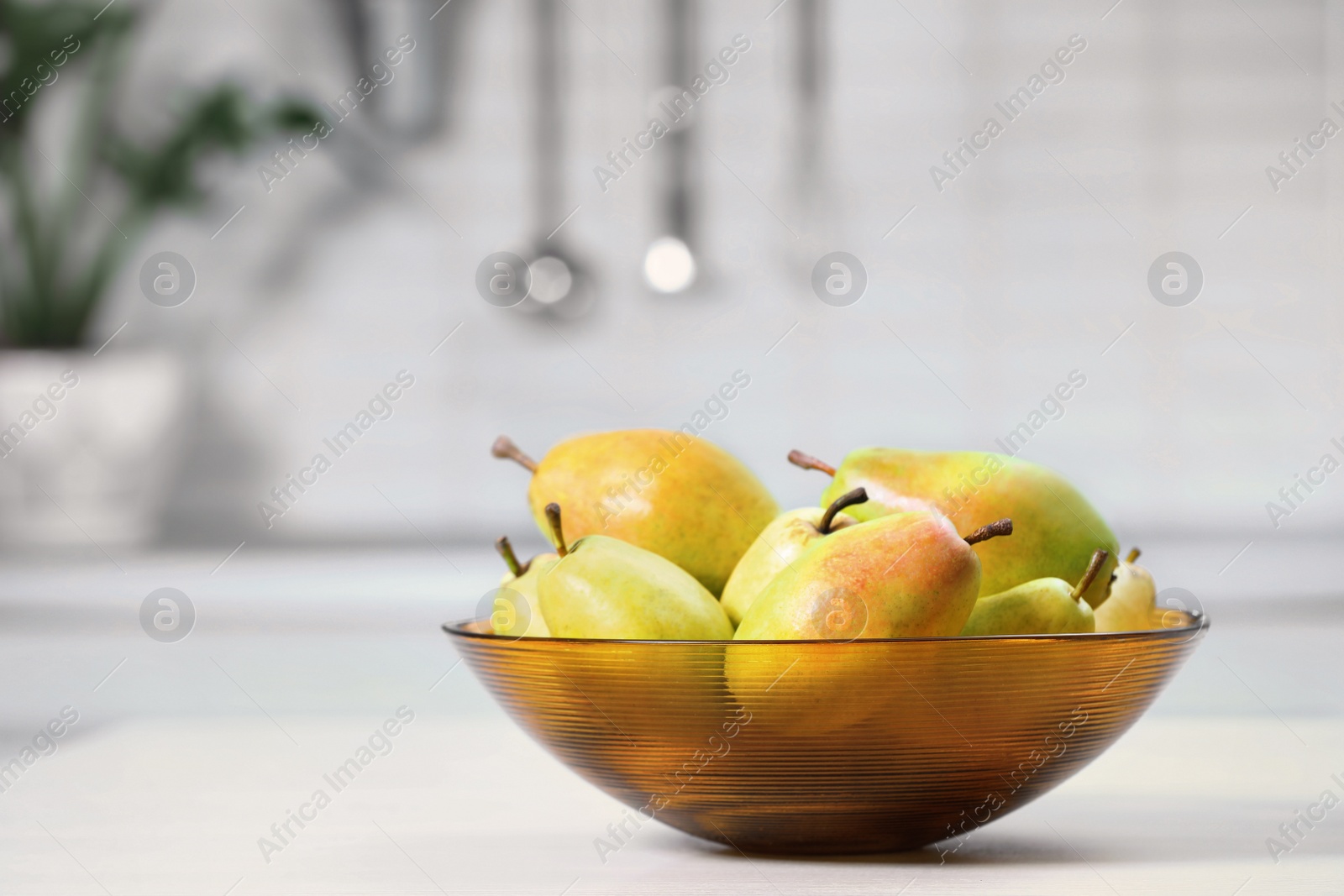 Photo of Fresh ripe pears on white table in kitchen. Space for text