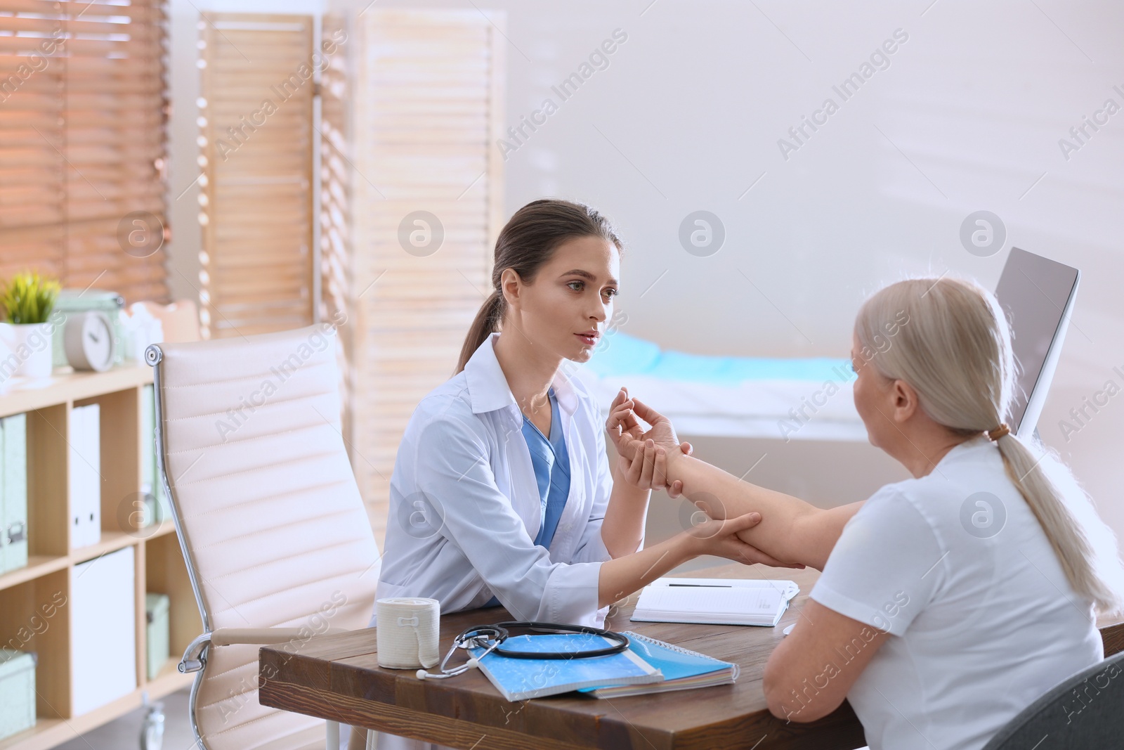 Photo of Female orthopedist examining patient with injured arm in clinic