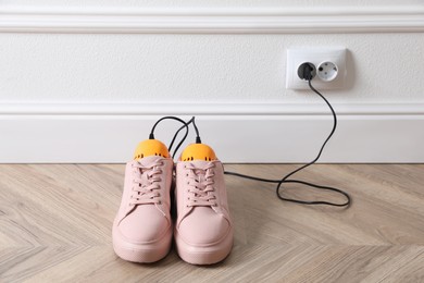 Photo of Pair of stylish shoes with modern electric footwear dryer on floor indoors