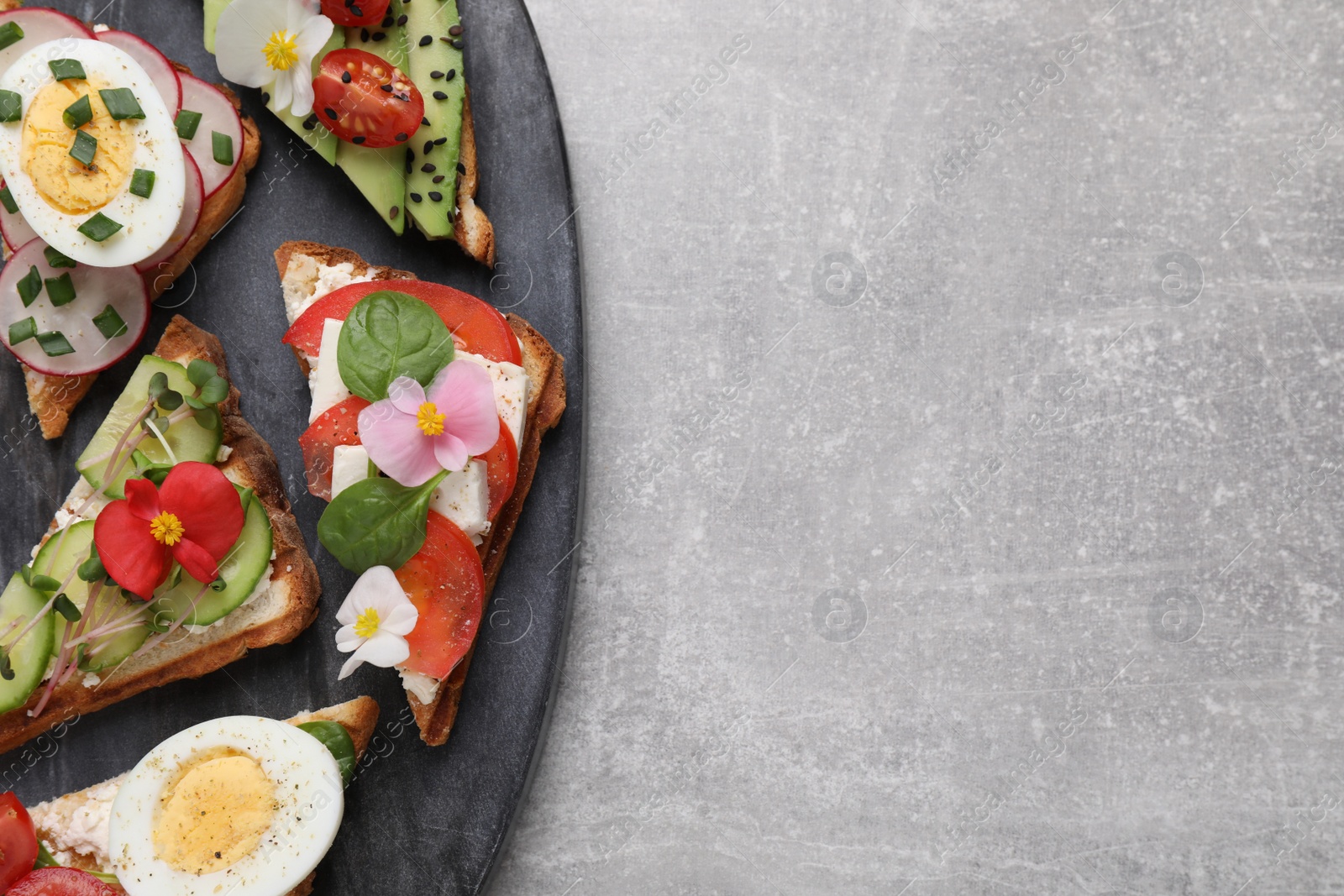 Photo of Different tasty sandwiches served on grey table, top view. Space for text