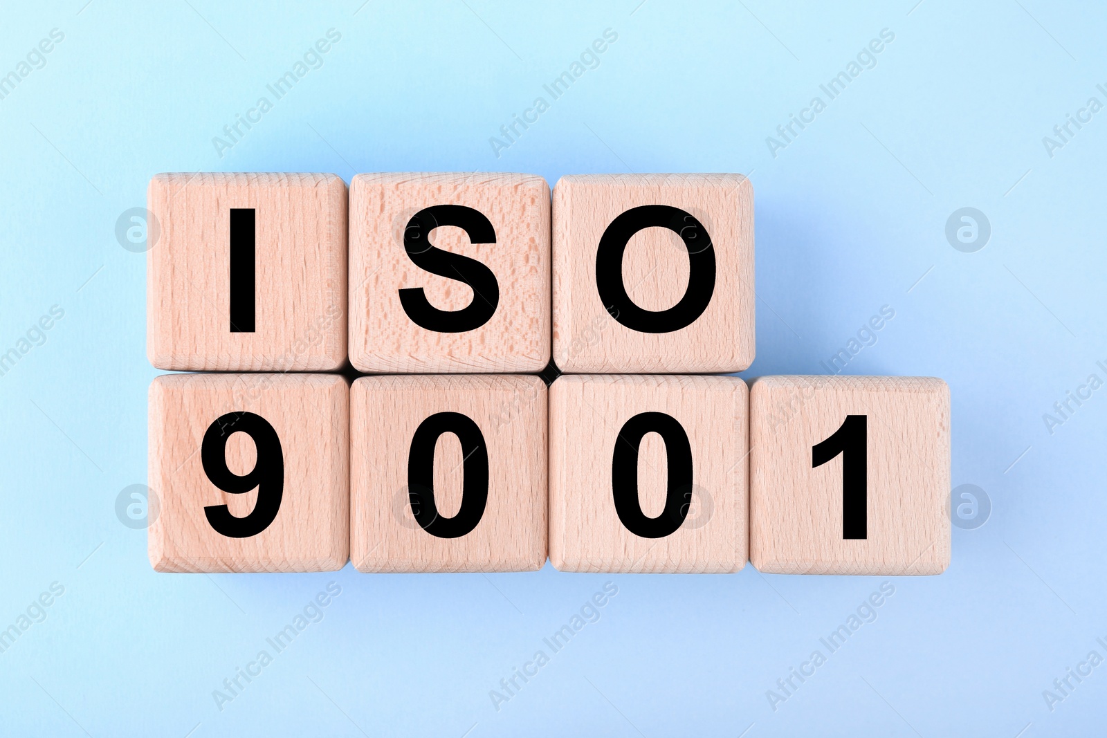 Photo of International Organization for Standardization. Wooden cubes with abbreviation ISO and number 9001 on light blue background, flat lay