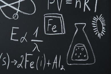 Photo of Different chemical formulas written with chalk on blackboard, closeup