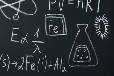 Different chemical formulas written with chalk on blackboard, closeup