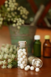 Photo of Bottles with homeopathic remedy and flowers on table