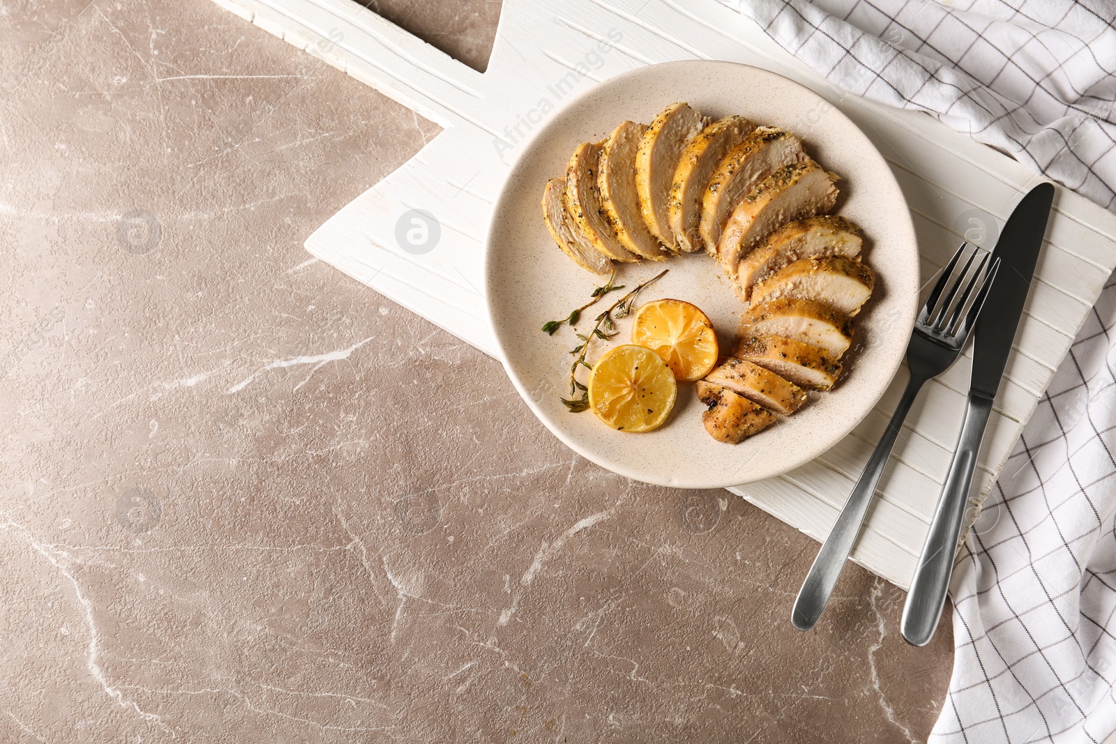 Photo of Tasty lemon chicken on brown marble table, flat lay. Space for text