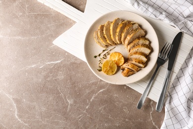 Tasty lemon chicken on brown marble table, flat lay. Space for text