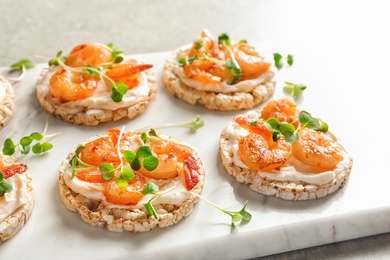 Photo of Delicious small sandwiches with shrimps on marble board