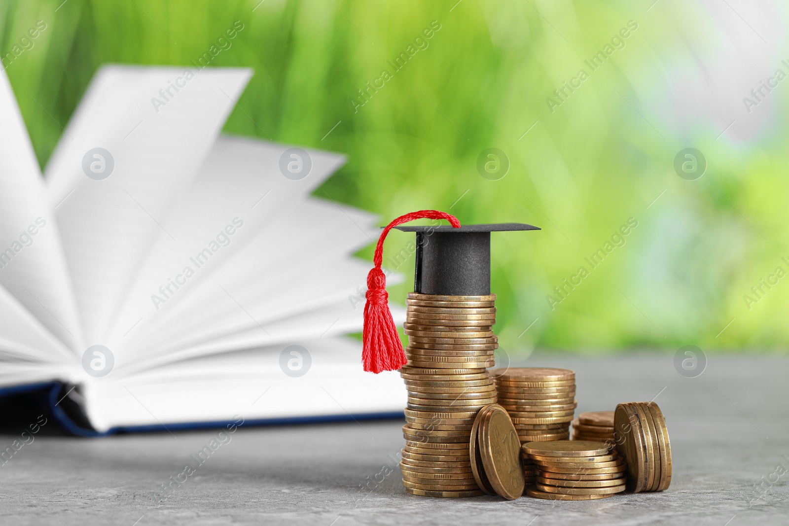 Photo of Scholarship concept. Coins and graduation cap on grey table, space for text