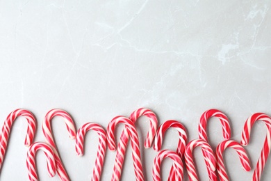 Sweet Christmas candy canes on grey background, flat lay. Space for text