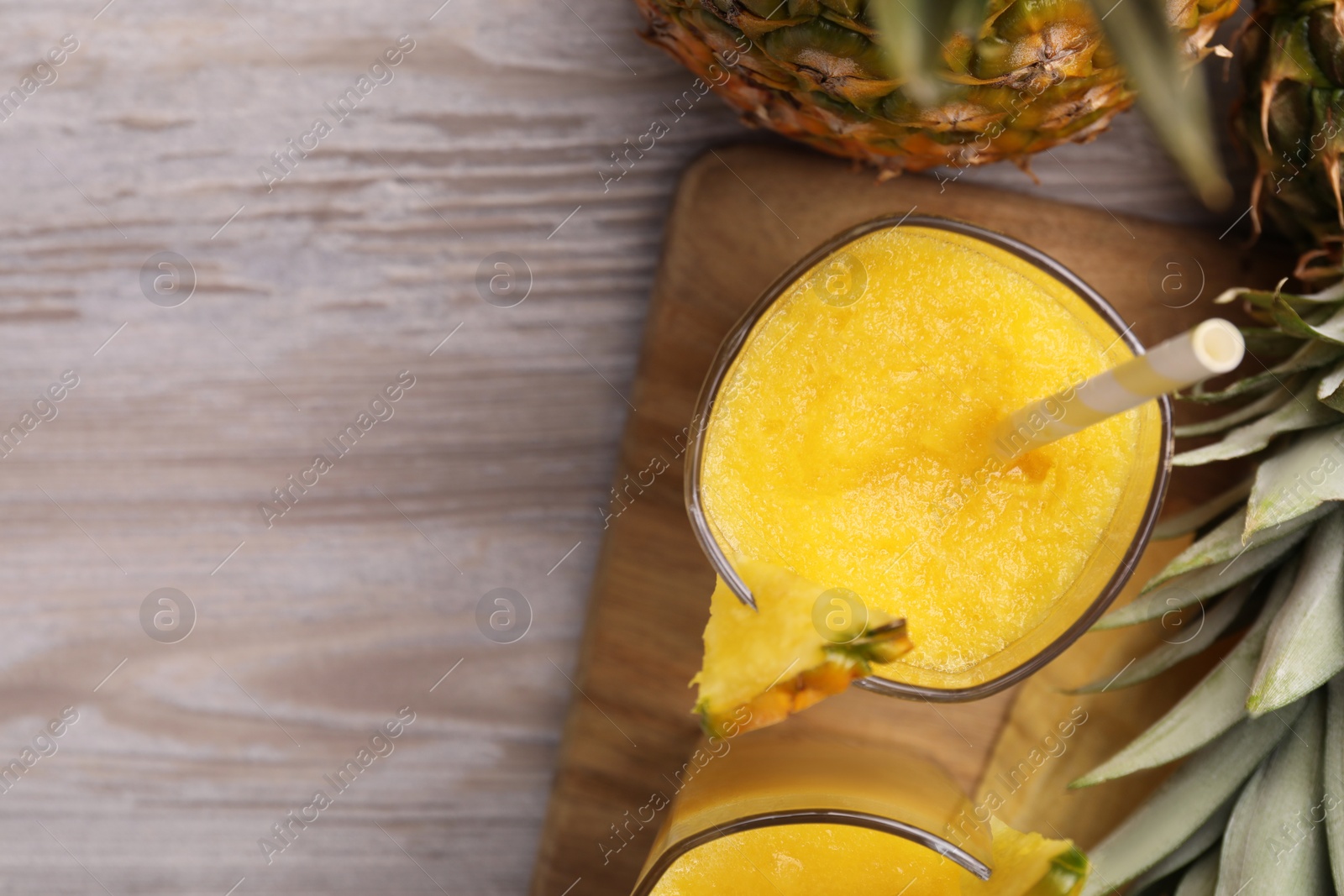 Photo of Tasty pineapple smoothie and fresh fruits on wooden table, flat lay. Space for text