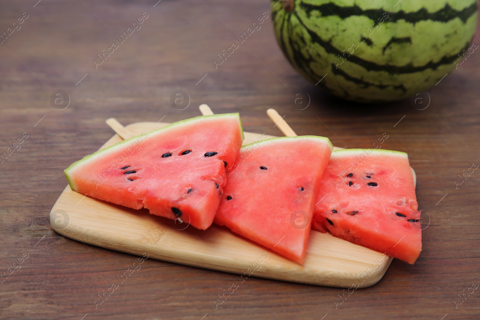 Photo of Whole and sliced delicious ripe watermelon on wooden table