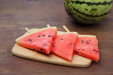 Photo of Whole and sliced delicious ripe watermelon on wooden table