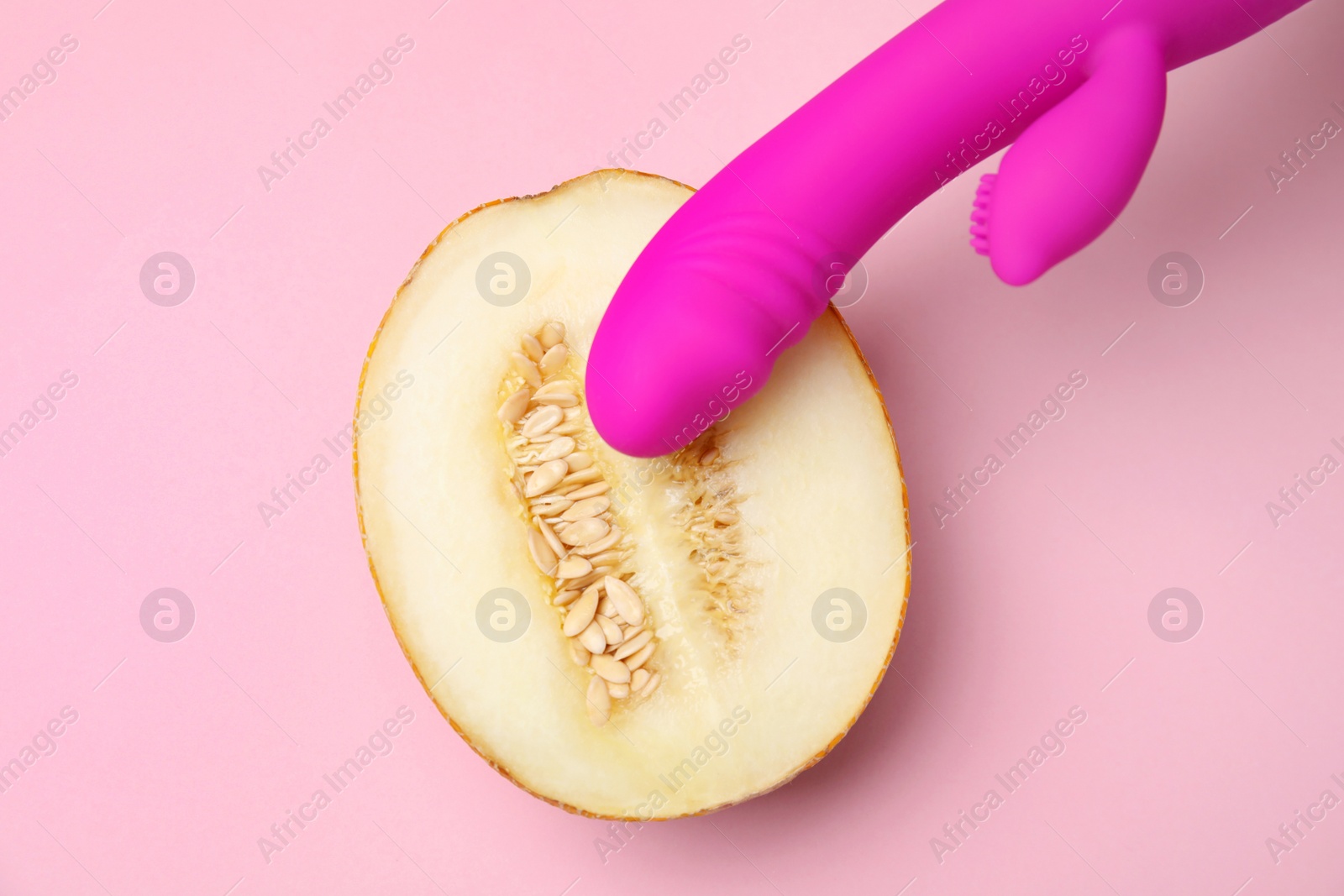 Photo of Half of melon and purple vibrator on pink background, flat lay. Sex concept