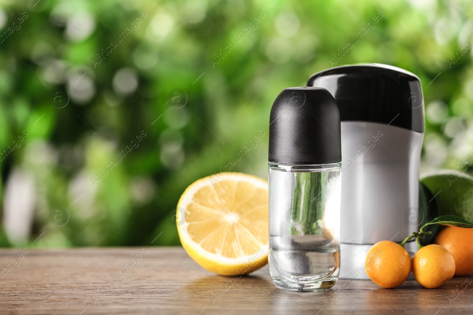 Photo of Different deodorants and citrus fruits on wooden table against blurred background. Space for text