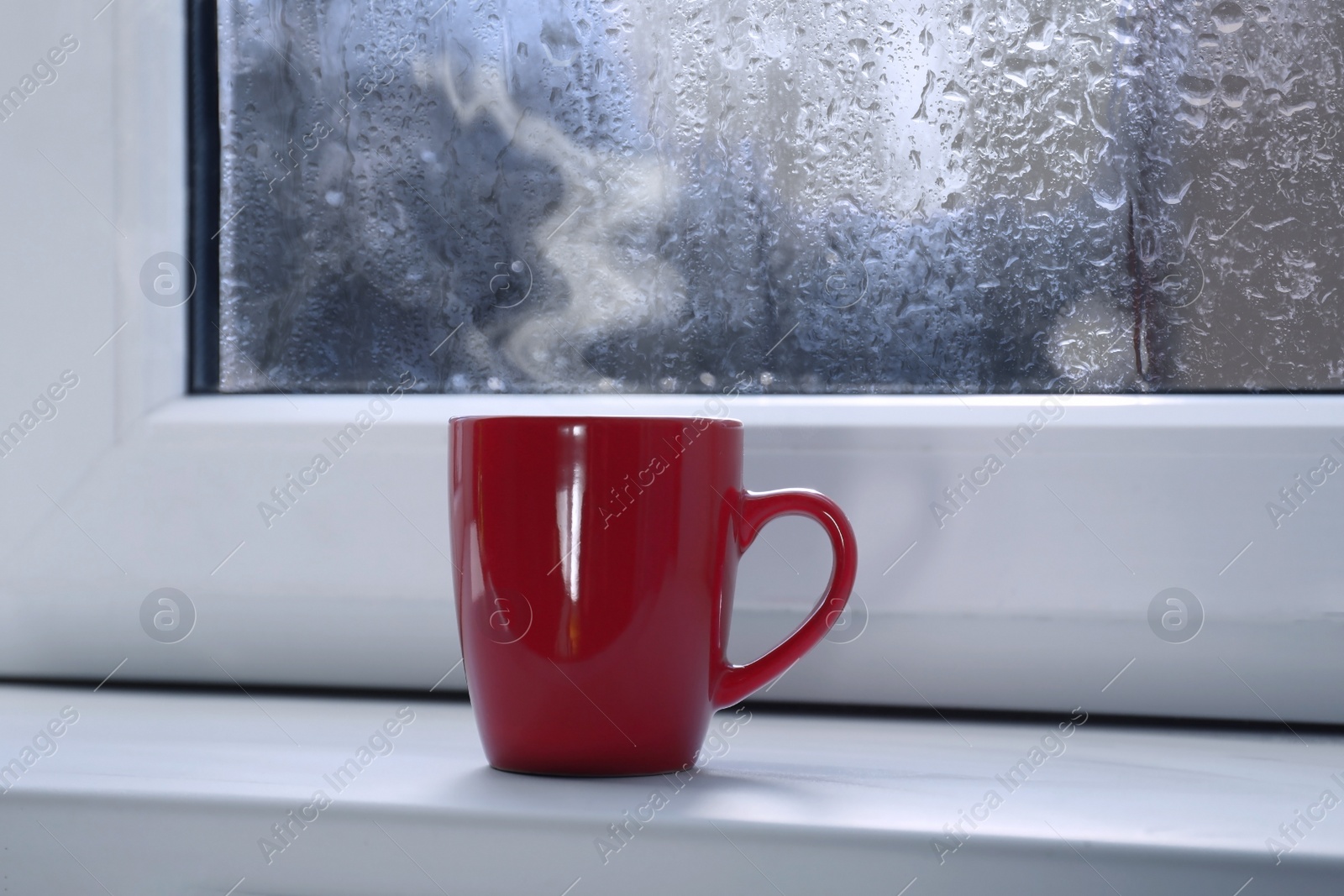 Image of Cup of hot drink near window on rainy day