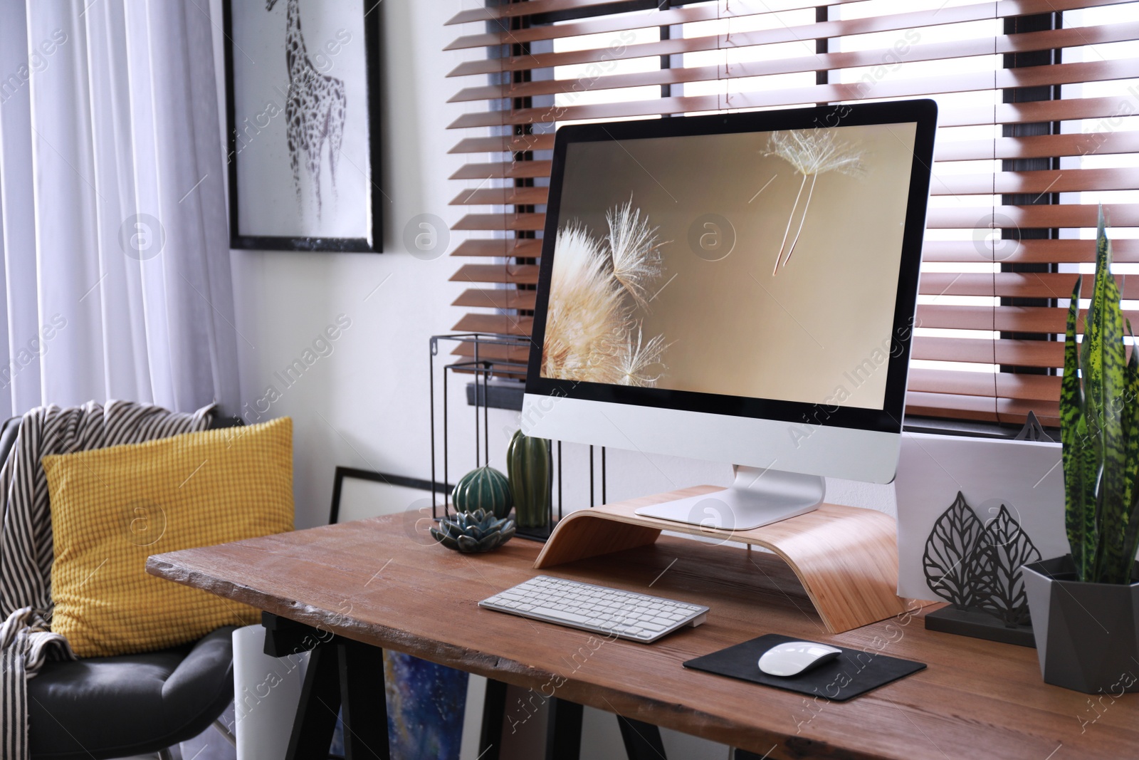 Photo of Comfortable workplace near window with horizontal blinds in room