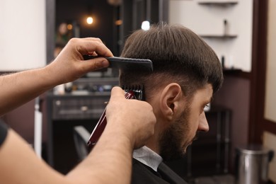 Photo of Professional hairdresser making stylish haircut in barbershop