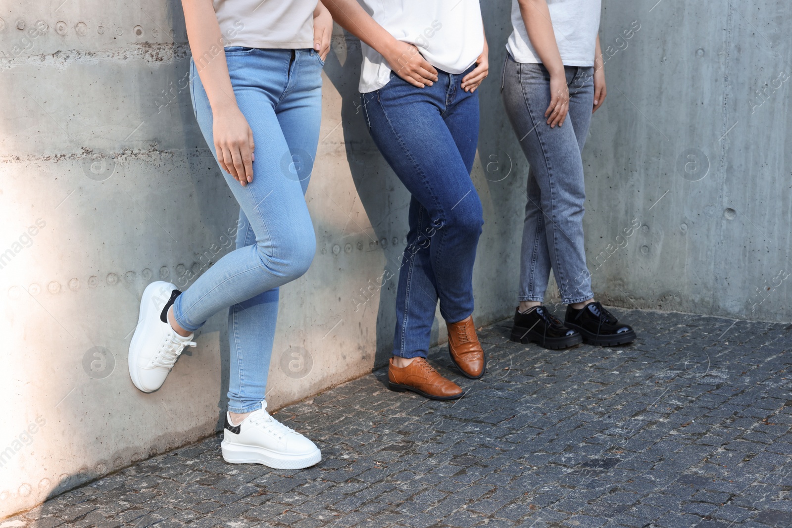 Photo of Women in stylish jeans near grey wall outdoors, closeup