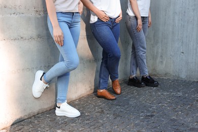 Photo of Women in stylish jeans near grey wall outdoors, closeup