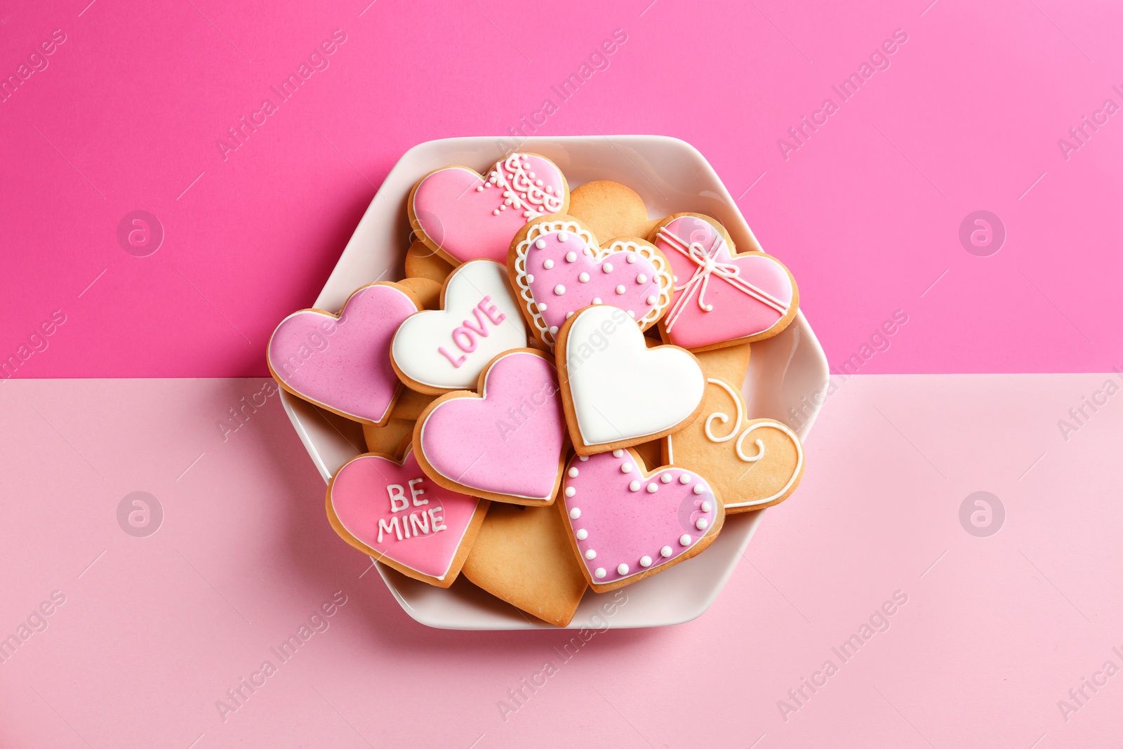 Photo of Plate with decorated heart shaped cookies on color background, top view. Valentine's day treat