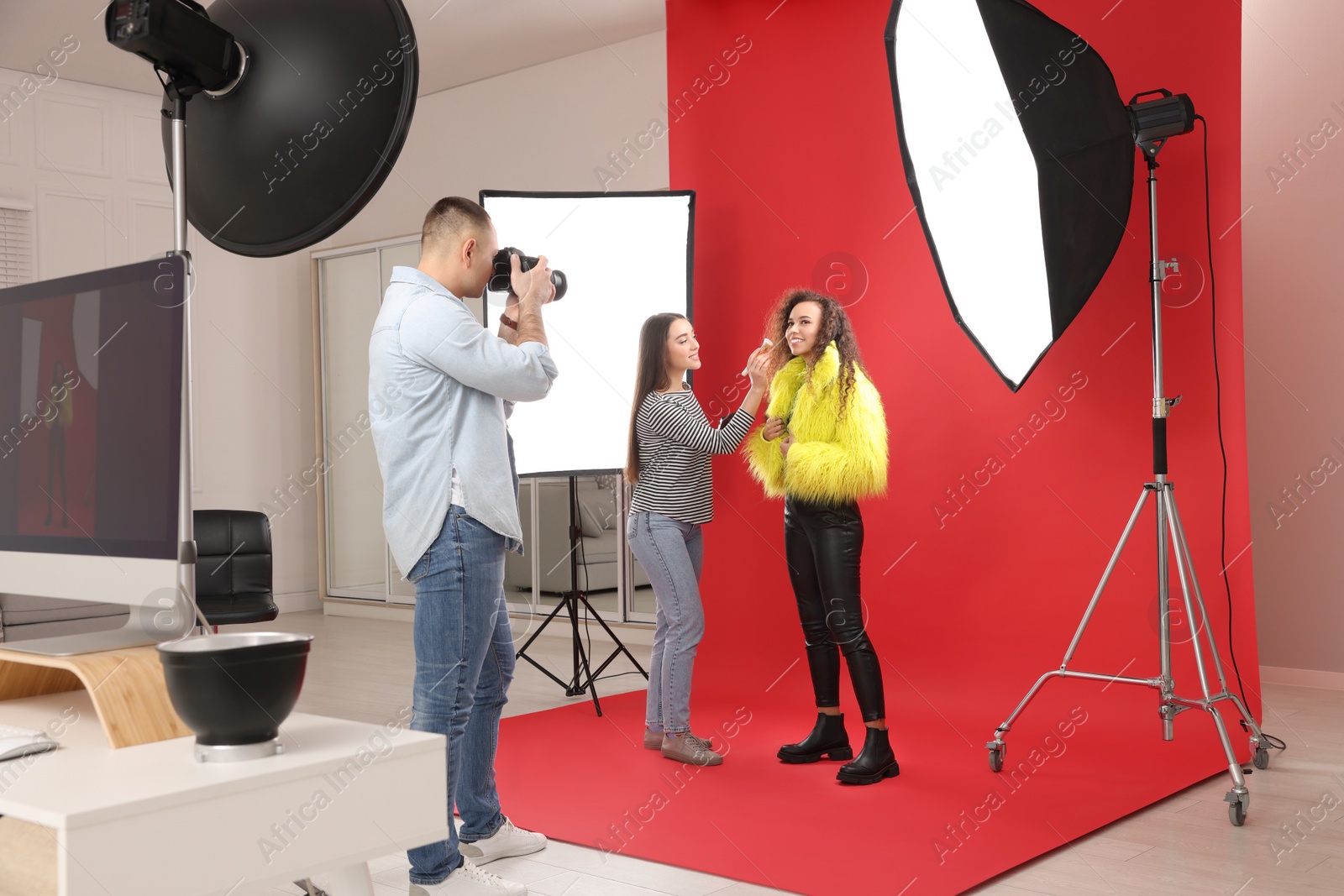 Photo of Professional photographer and makeup artist with model in studio