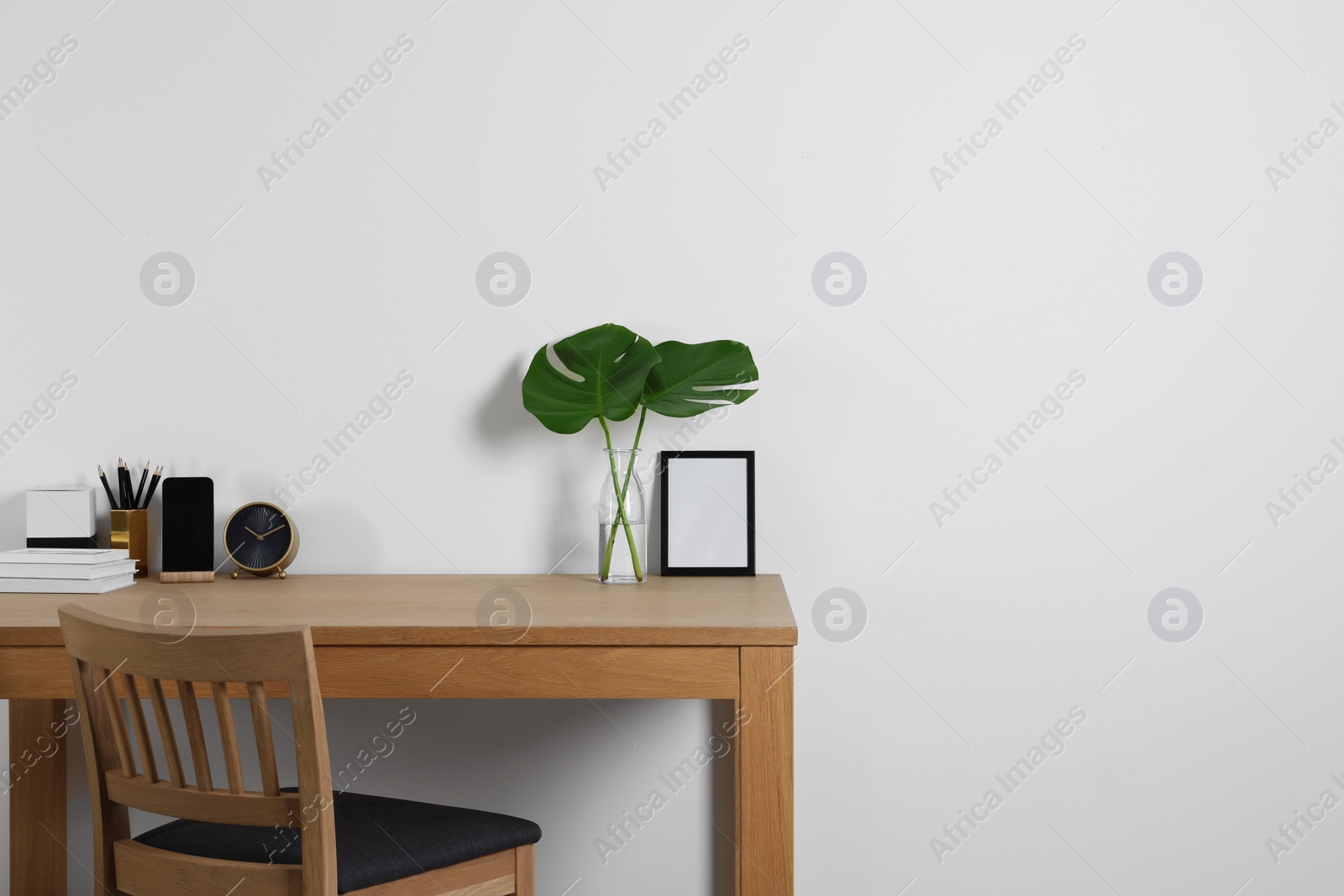 Photo of Comfortable workplace with wooden desk near white wall at home