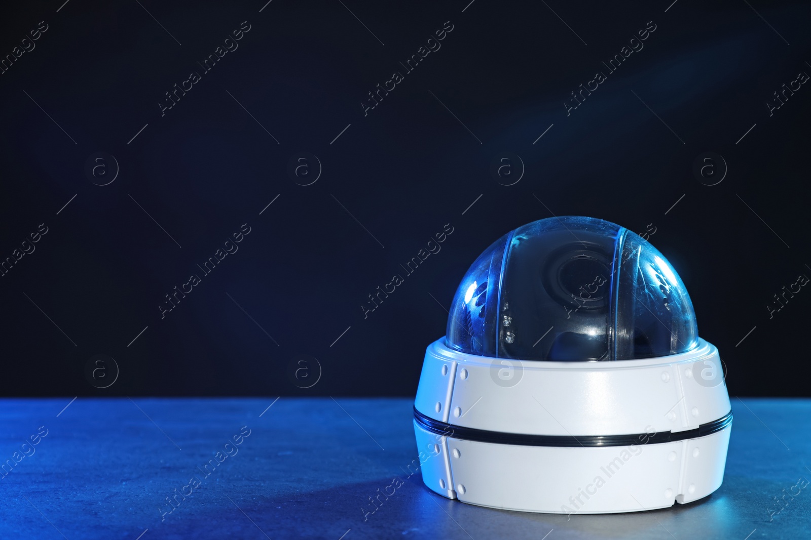 Photo of Modern security CCTV camera on table against dark background