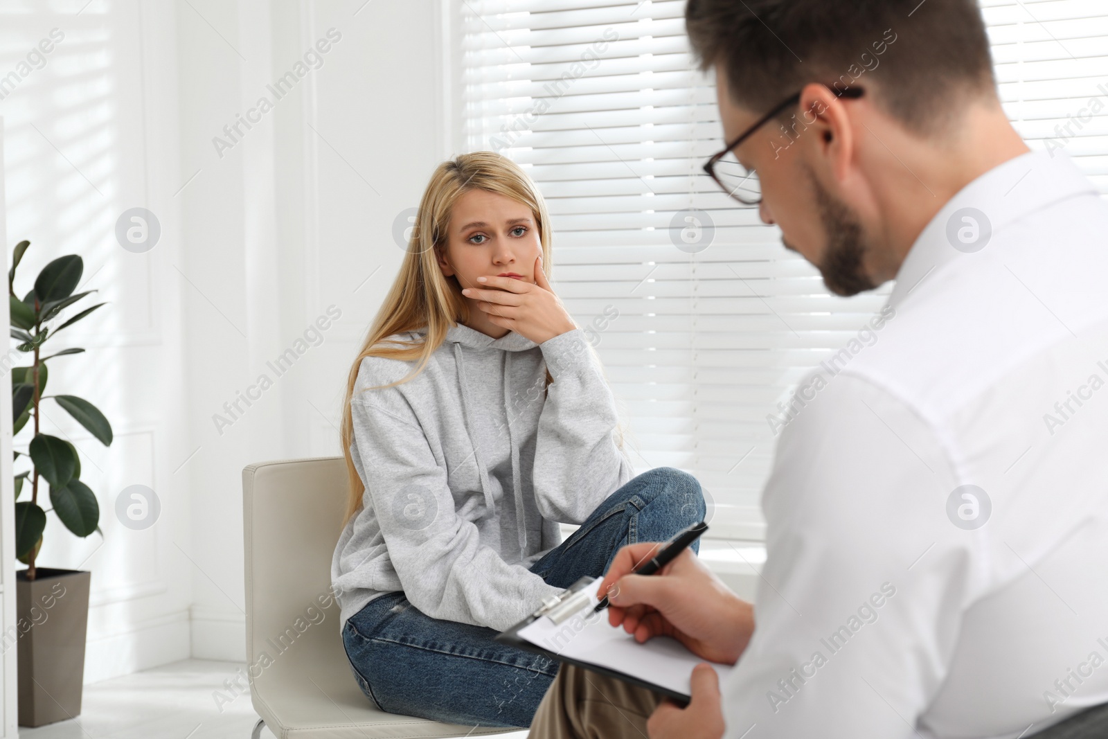 Photo of Psychotherapist working with drug addicted young woman indoors