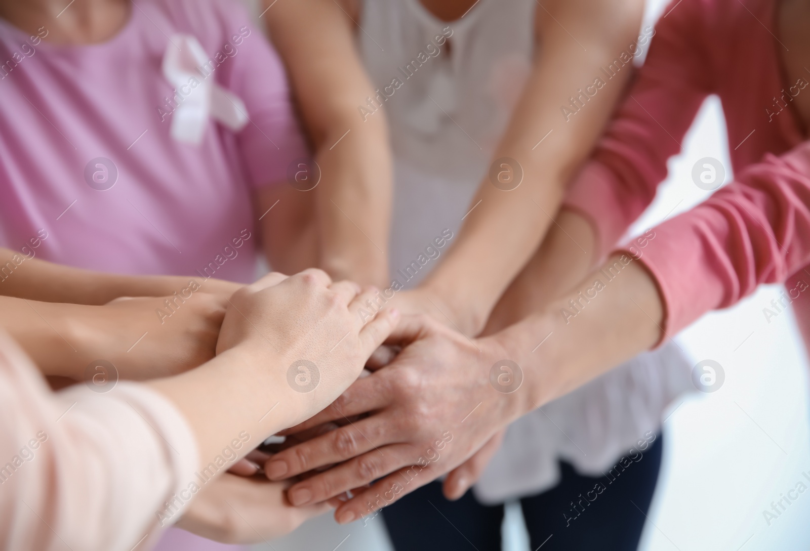 Photo of Group of women with silk ribbons joining hands, closeup. Breast cancer awareness concept