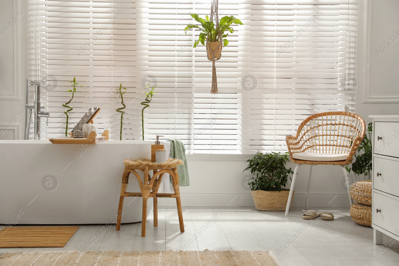 Photo of Stylish white tub and green houseplants in bathroom. Interior design