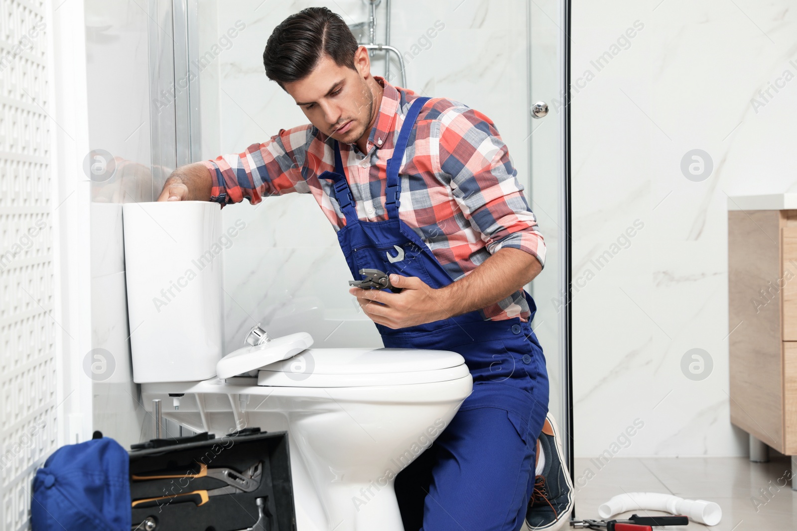 Photo of Professional plumber working with toilet bowl in bathroom