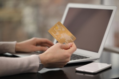 Photo of Woman with credit card using laptop for online shopping at table, closeup