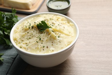 Photo of Bowl of delicious mashed potato with parsley on wooden table. Space for text