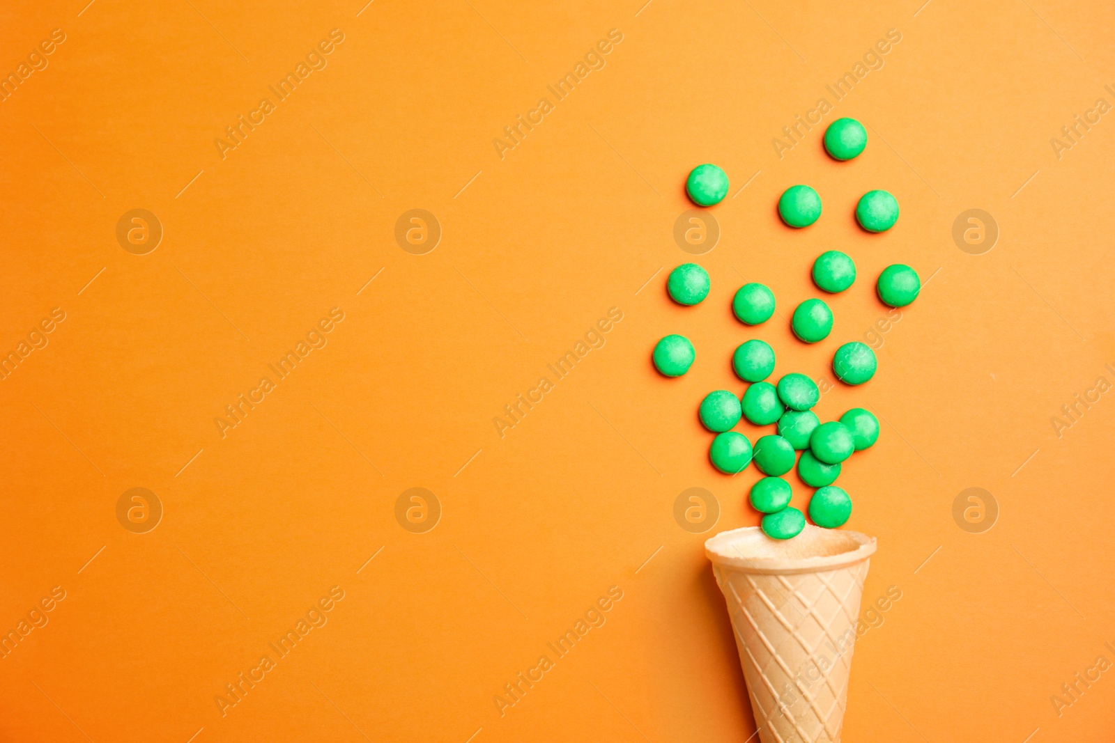 Photo of Flat lay composition with candies and ice cream cone on color background. Space for text