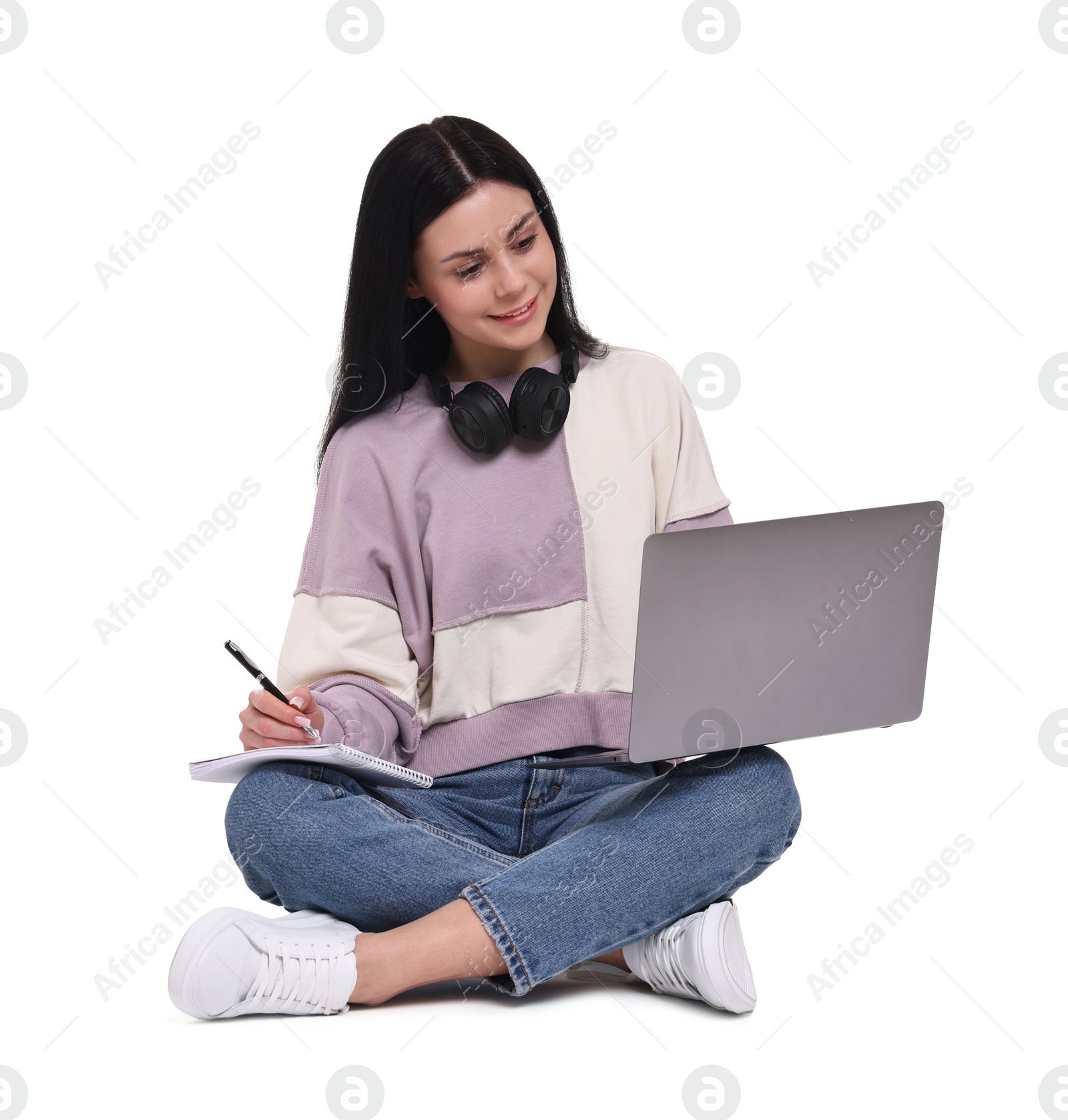 Photo of Smiling student with laptop writing in notebook on white background
