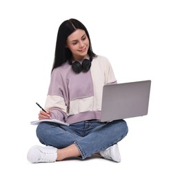 Smiling student with laptop writing in notebook on white background